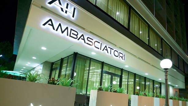 A building with a sign reading "AMBASSACIATORI" and a modern design with large windows and decorative planters. - Hotel Ambasciatori (Cesenatico)