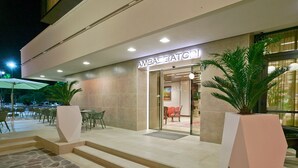 A hotel entrance with a modern design, featuring a stone-tiled entrance, a glass door, and a sign that reads "AMBASSADOR." - Hotel Ambasciatori (Cesenatico)