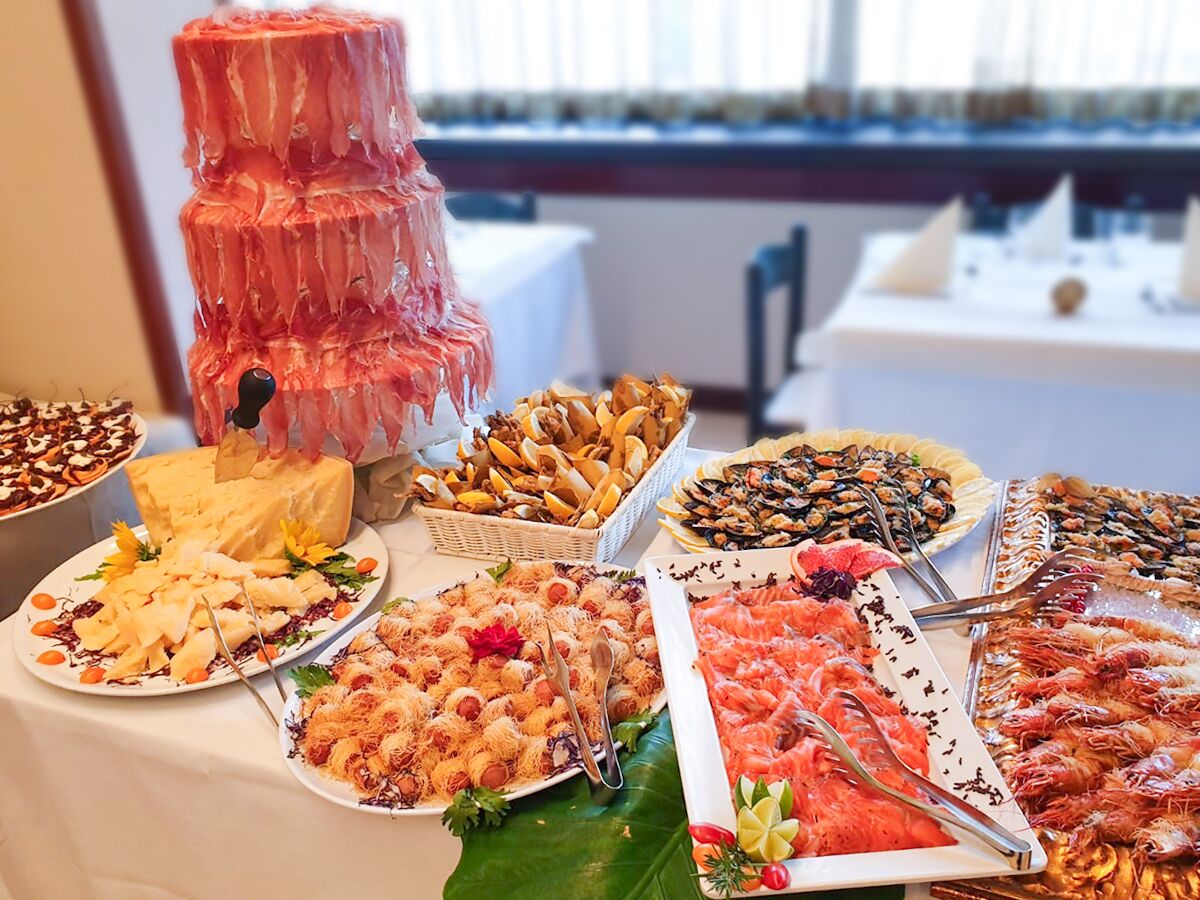 Una mesa de buffet con diversos alimentos, entre ellos mariscos, quesos y pasteles.