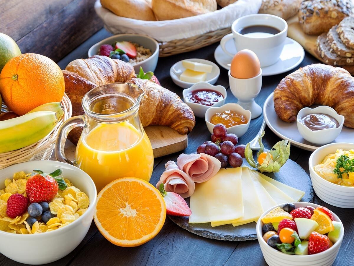 Ein reichhaltiges Frühstücksbuffet mit Croissants, Käse, Obst und Getränken.