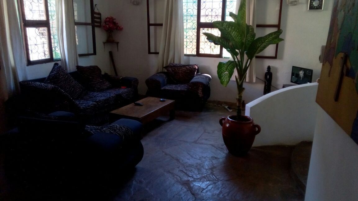 Un salon comprenant un canapé, un fauteuil, une table basse et une grande plante en pot.