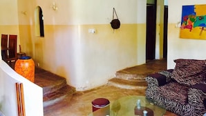 A living room with a glass coffee table, a zebra-patterned sofa, a colorful painting, and a staircase leading to another room. - Akogo House (Mombasa)