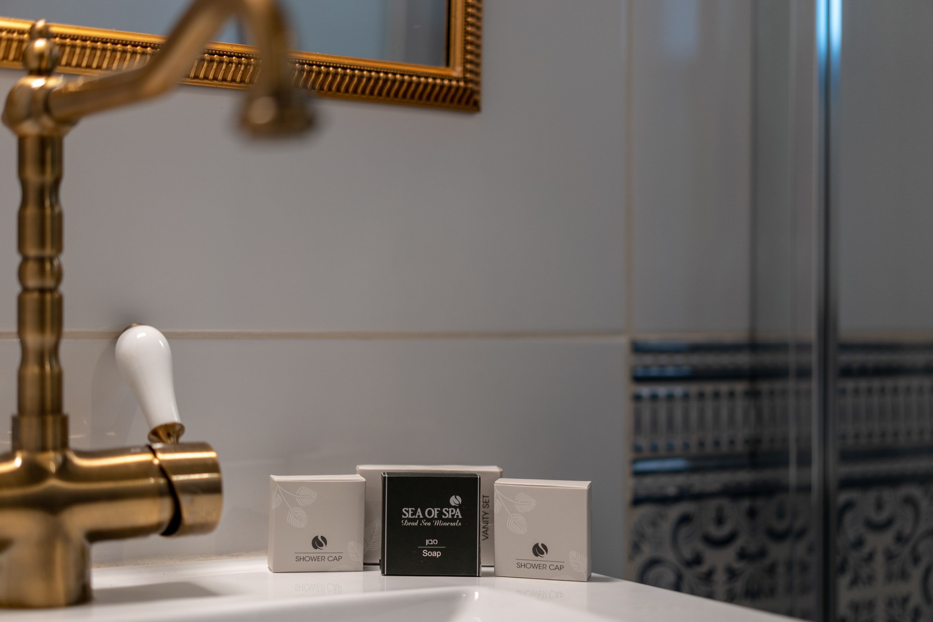 A bathroom with a gold faucet, a mirror, and three boxes labeled 'SEA OF SPA' on a white sink.