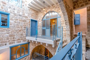 Un bâtiment en pierre doté d’un balcon, d’un escalier et d’une porte.