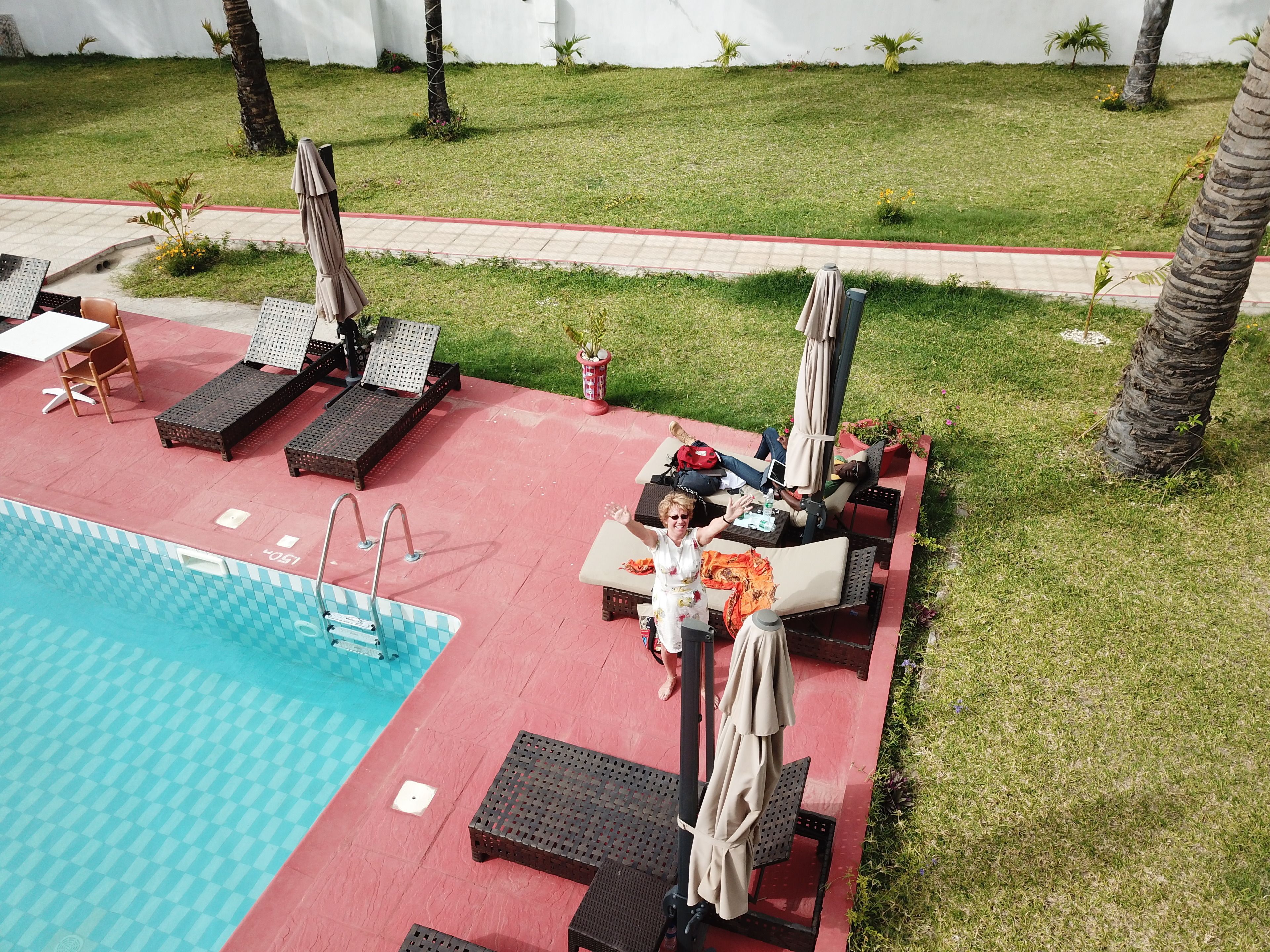 A poolside area with lounge chairs, umbrellas, and a swimming pool.