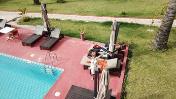 A poolside area with lounge chairs, umbrellas, and a swimming pool.