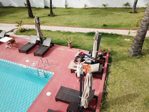 A poolside area with lounge chairs, umbrellas, and a swimming pool.