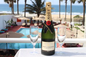 A bottle of Moët & Chandon champagne and two glasses on a table with a pool and beach view.