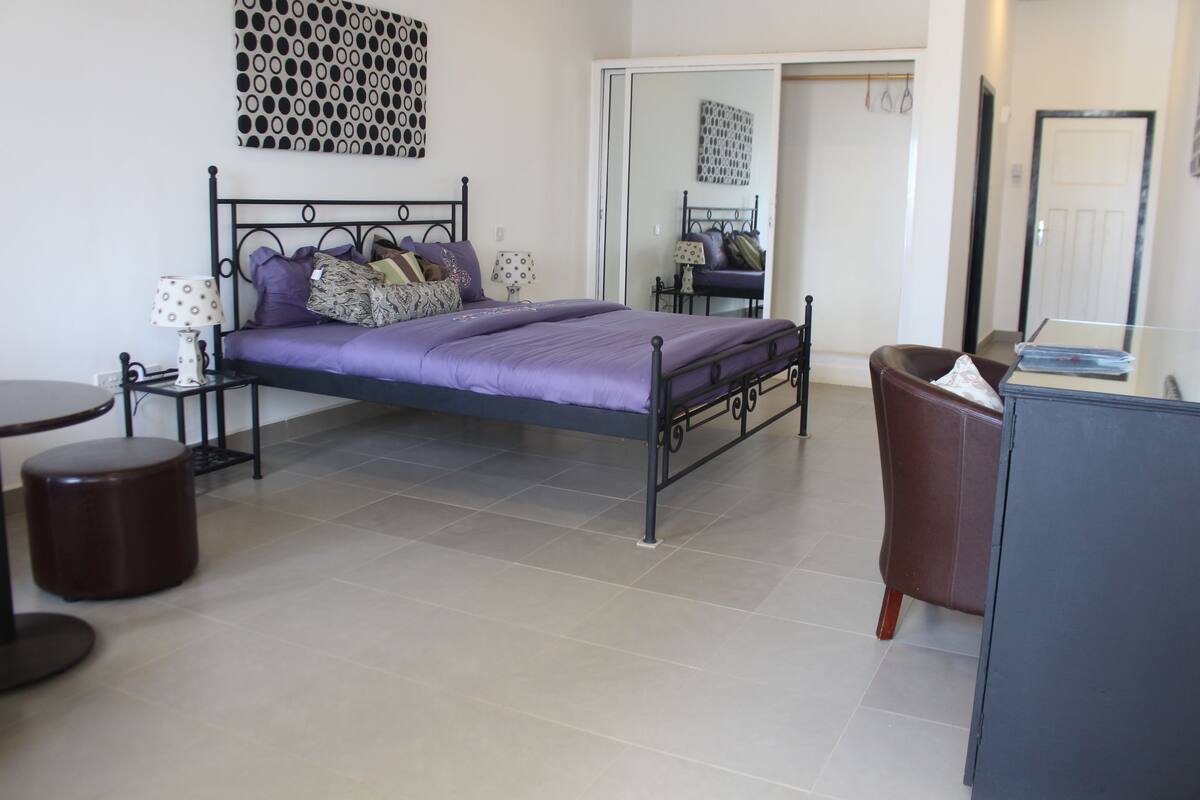 A neatly arranged bedroom with a bed, bedside tables, a chair, and a desk.