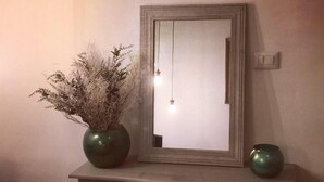 A small, simple console table with a mirror, two green vases, and a single light bulb. - B&B Miseno23 (Bacoli)