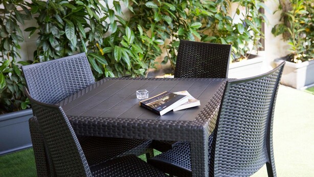 A black wicker table with four chairs, a book, and a glass of water. - B&B Miseno23 (Bacoli)