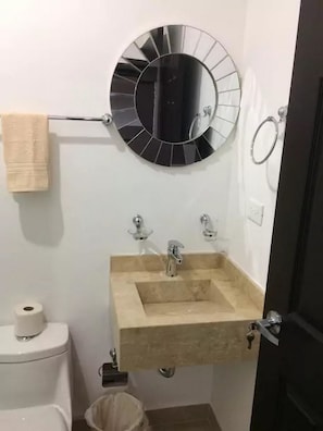 Une salle de bain avec des toilettes, un lavabo, une serviette et un miroir.