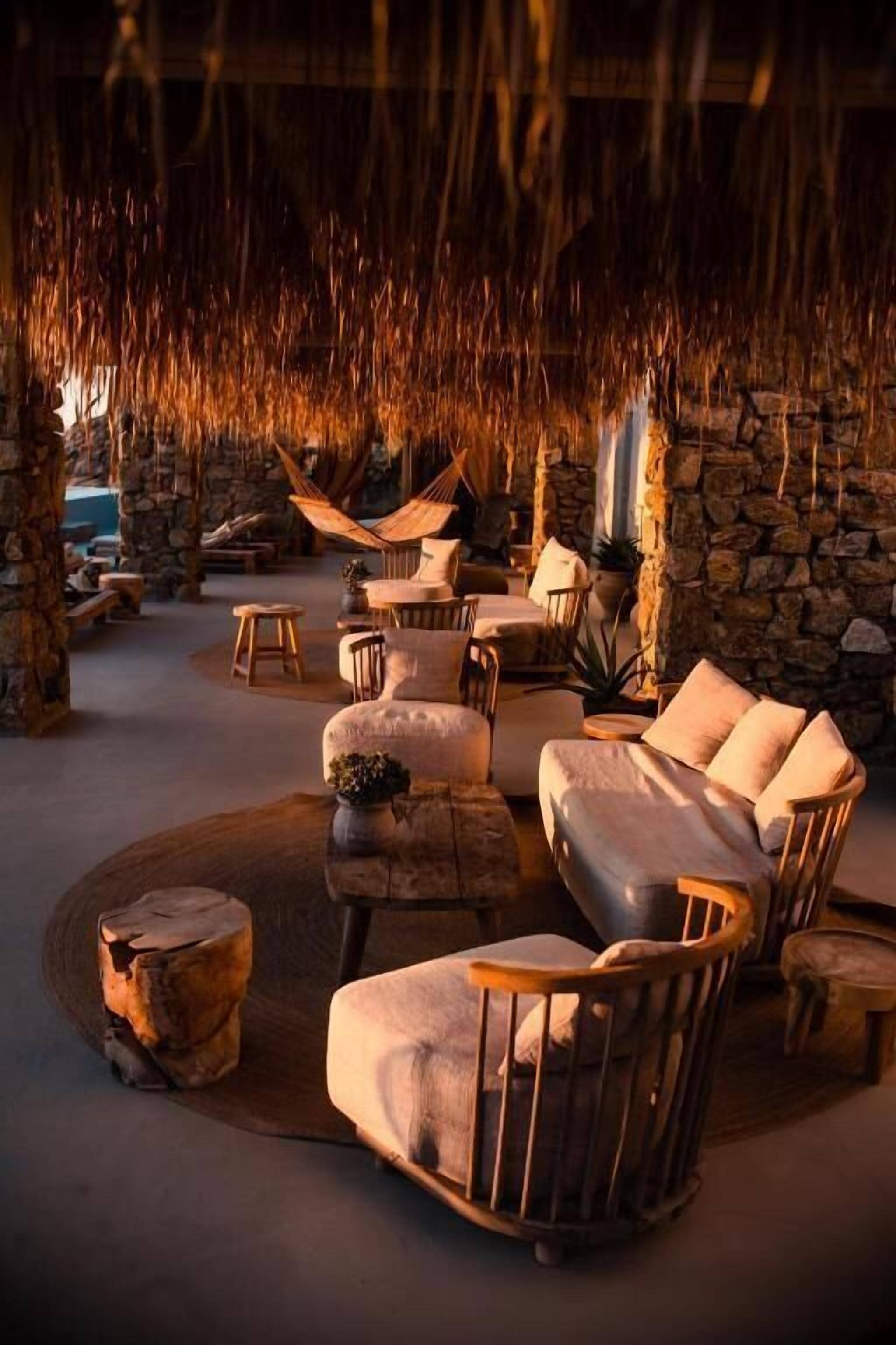 A cozy lounge area with a stone wall, a hammock, and a variety of seating options including a sofa and chairs.