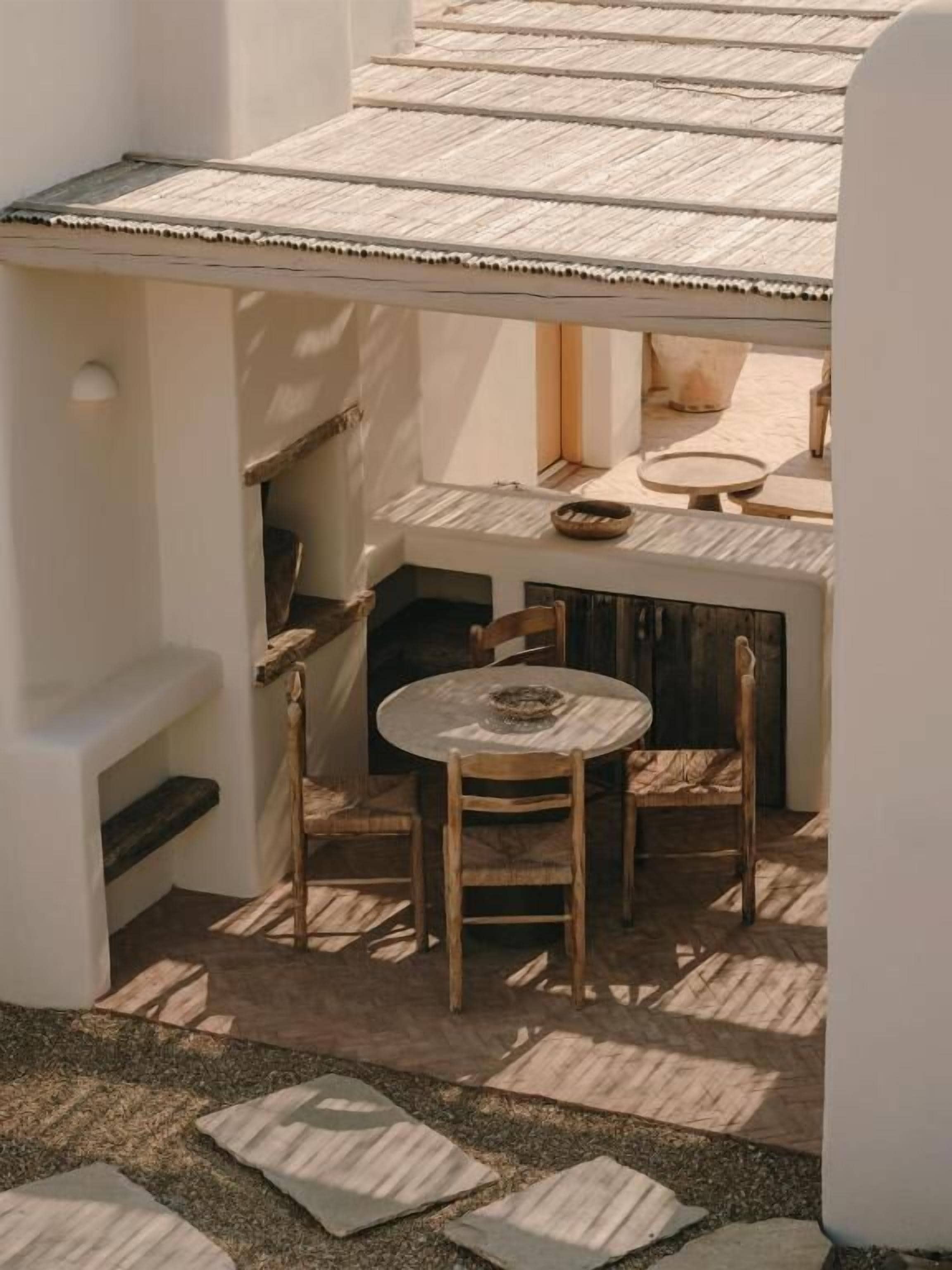 A small outdoor seating area with a table and chairs, a bench, and a potted plant.