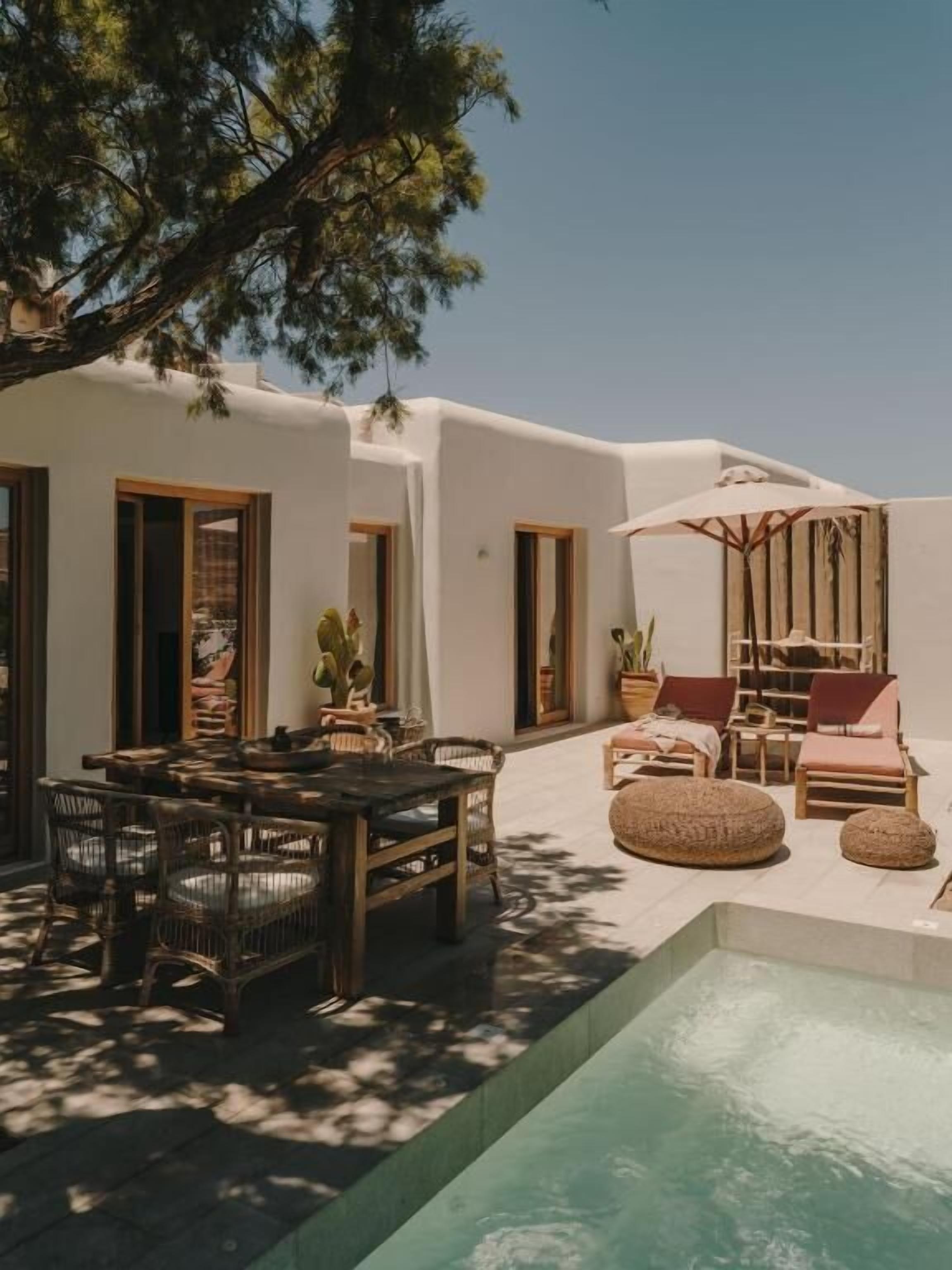 A poolside area with a dining table and chairs, lounge chairs, and a small pool.