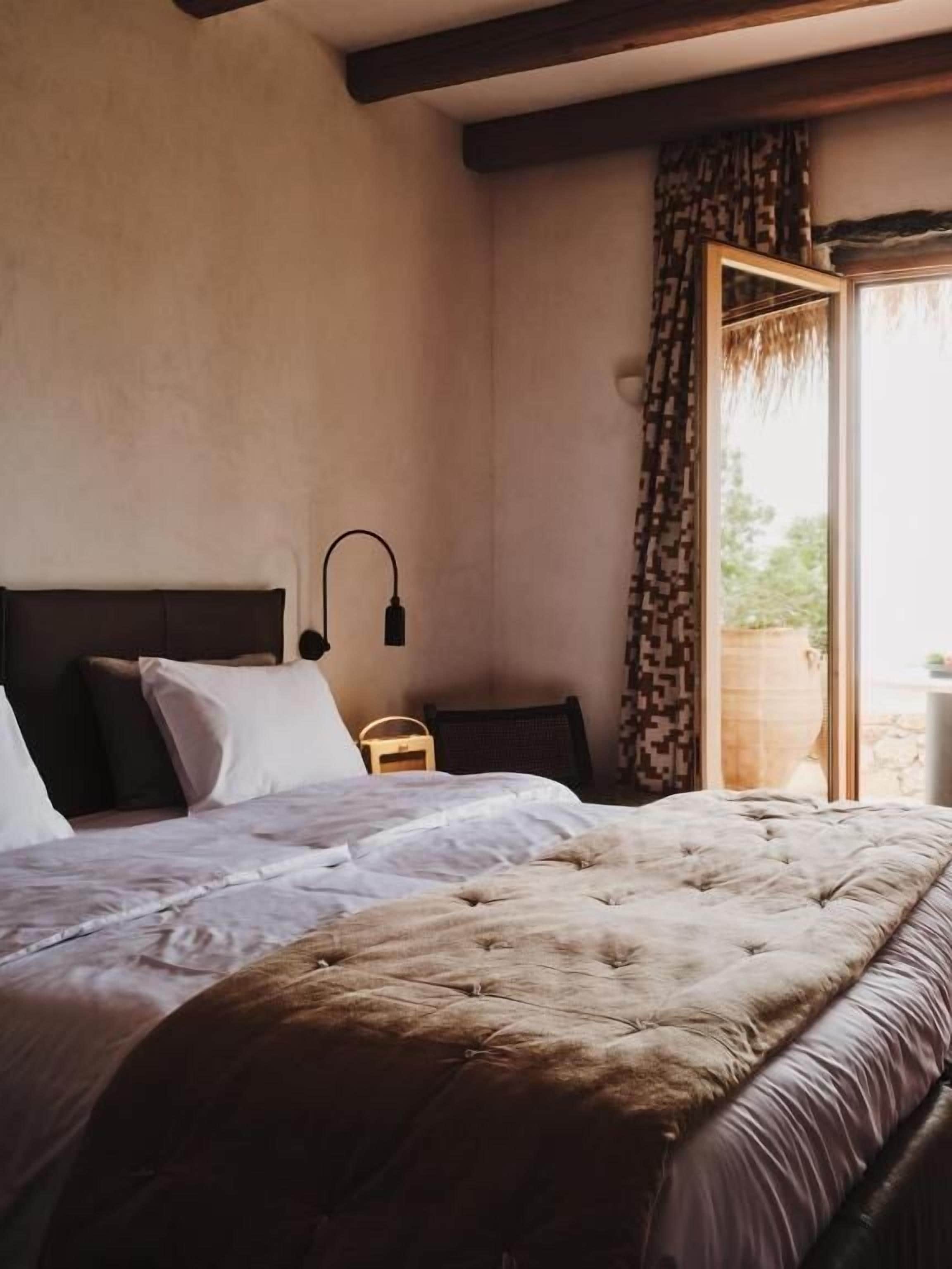 Una camera da letto con un letto, un comodino, una lampada e vista sull'esterno.