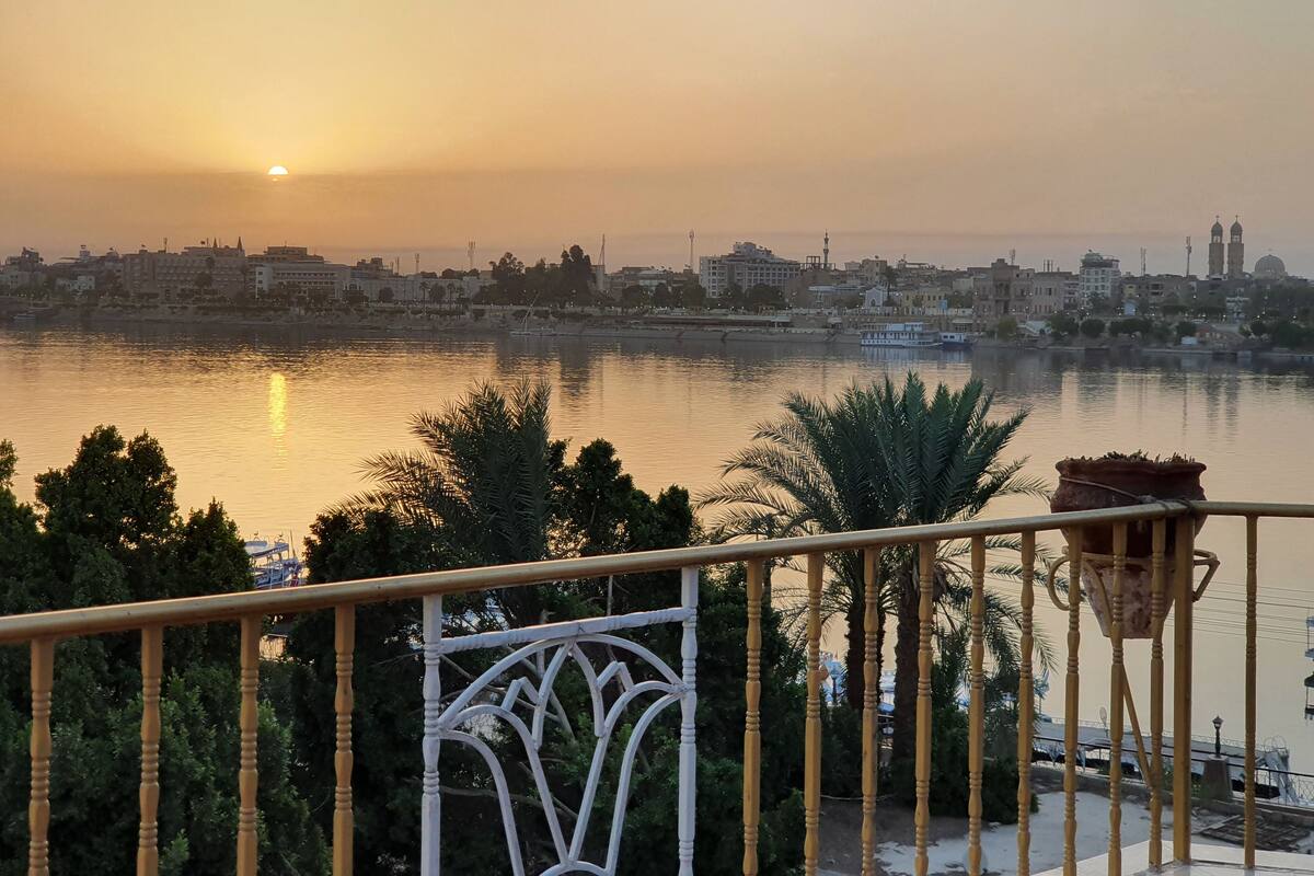 A balcony with a view of a cityscape at sunset, including a river and buildings in the background.