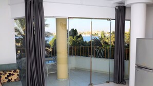 A balcony with a glass door, a sofa with a floral pattern, and a refrigerator. - Spring Hotel Luxor (Luxor)