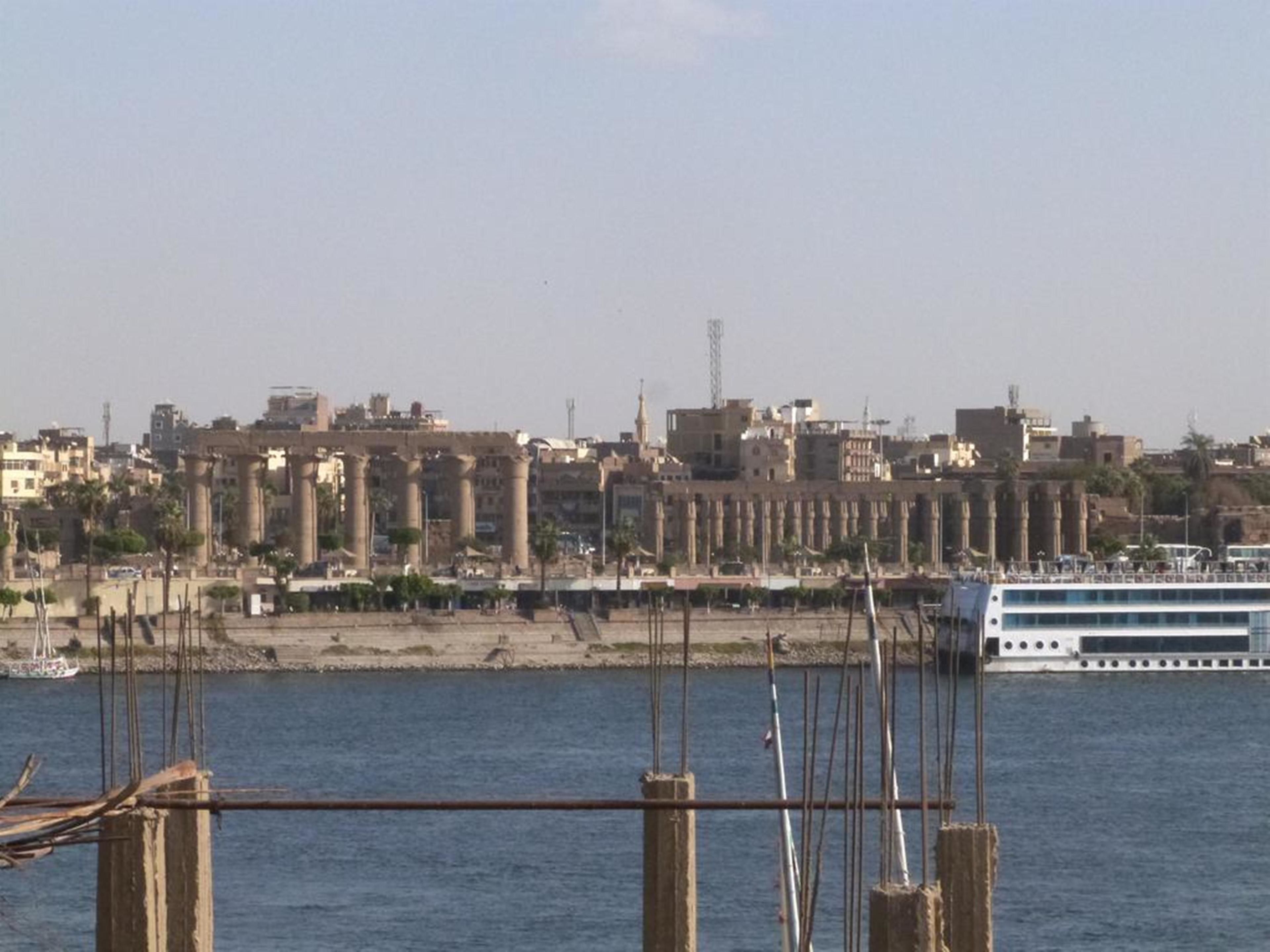 A coastal cityscape with ancient ruins and modern buildings.