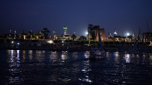 A nighttime waterfront scene with boats, illuminated buildings, and a prominent tower. - Spring Hotel Luxor (Luxor)