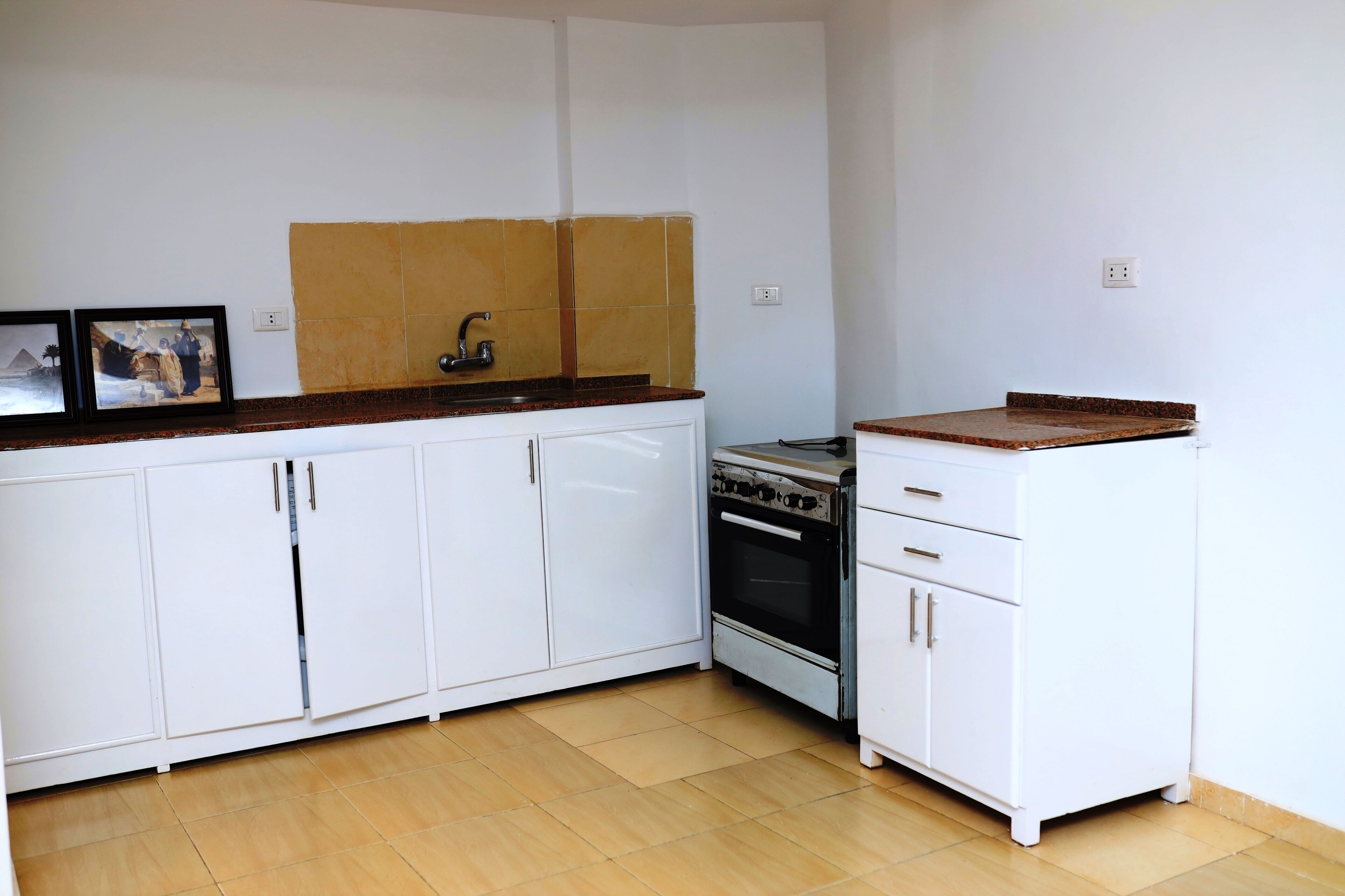 Una cocina con armarios blancos, una estufa y un lavabo.