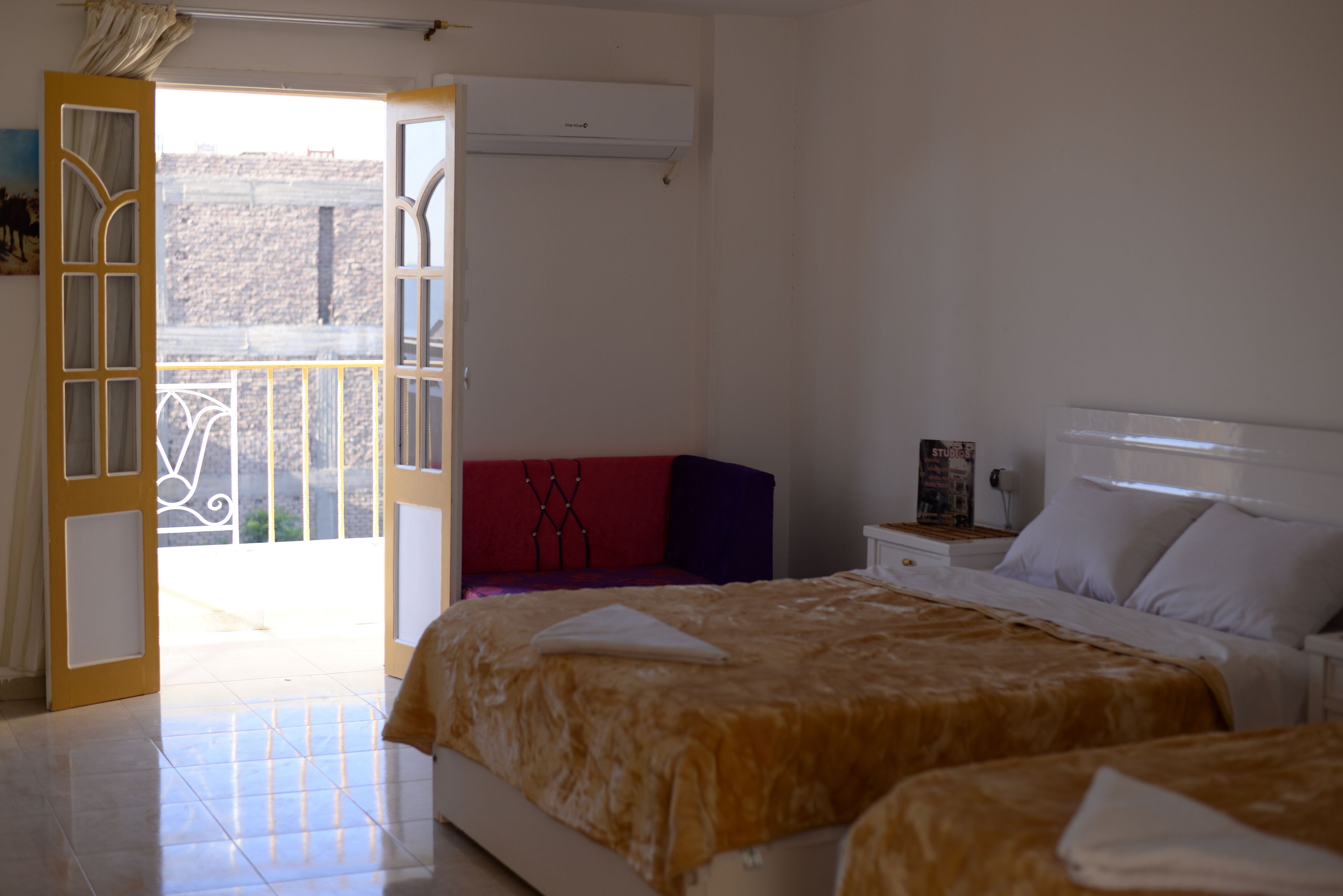 Ein Schlafzimmer mit zwei Betten, einem Balkon und einem roten Sofa.