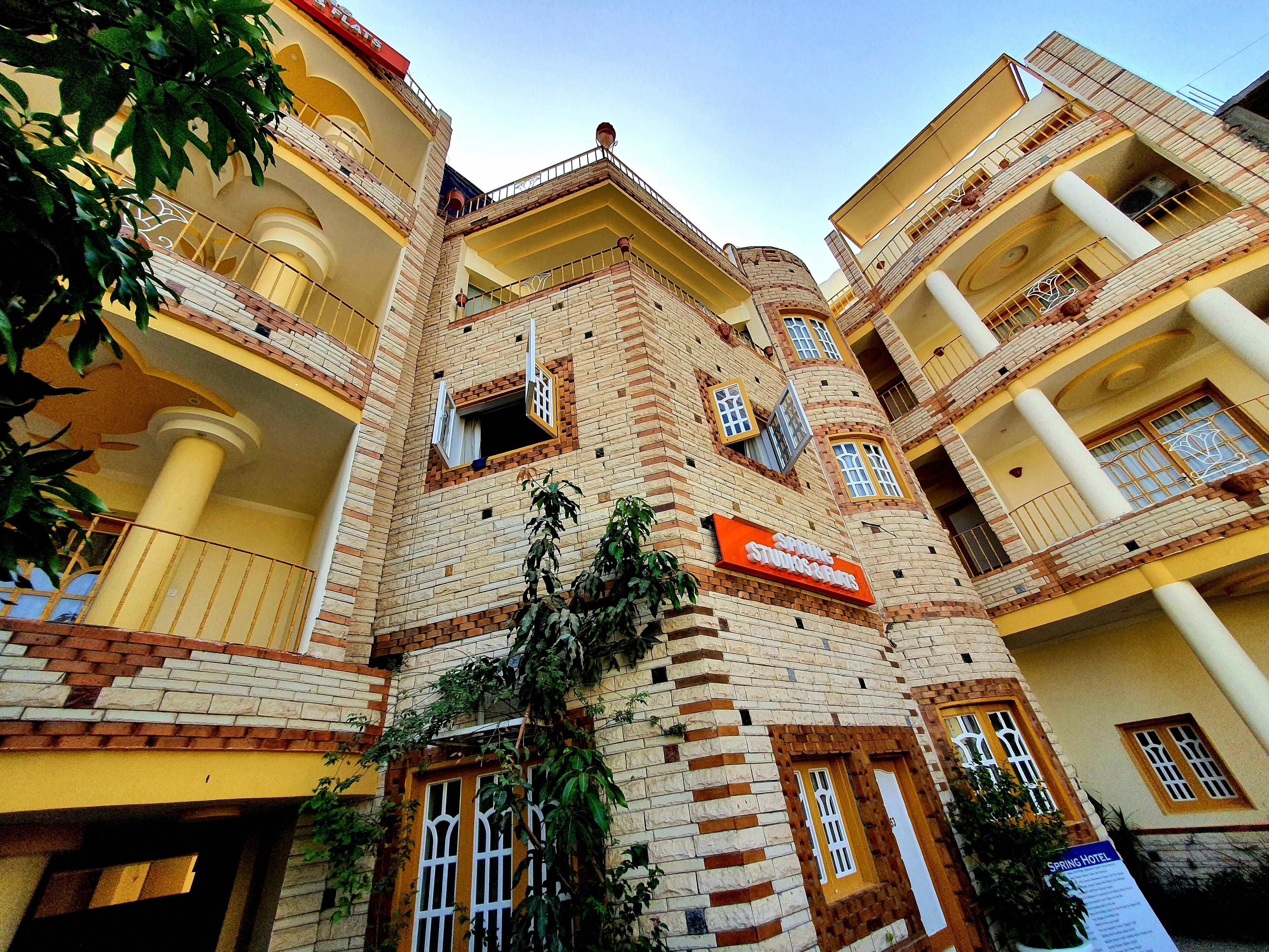 A multi-story hotel with a brick facade, multiple balconies, and a sign indicating it is a hotel.