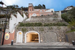 Un edificio con fachada de piedra, una puerta blanca y una escalera que lleva a un nivel superior.