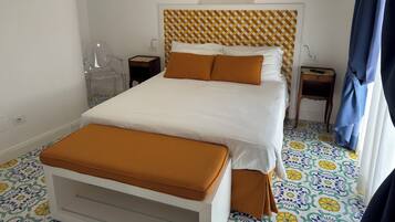 Una camera d'albergo ordinata con un letto, un comodino, una sedia e un tavolino con un telecomando.