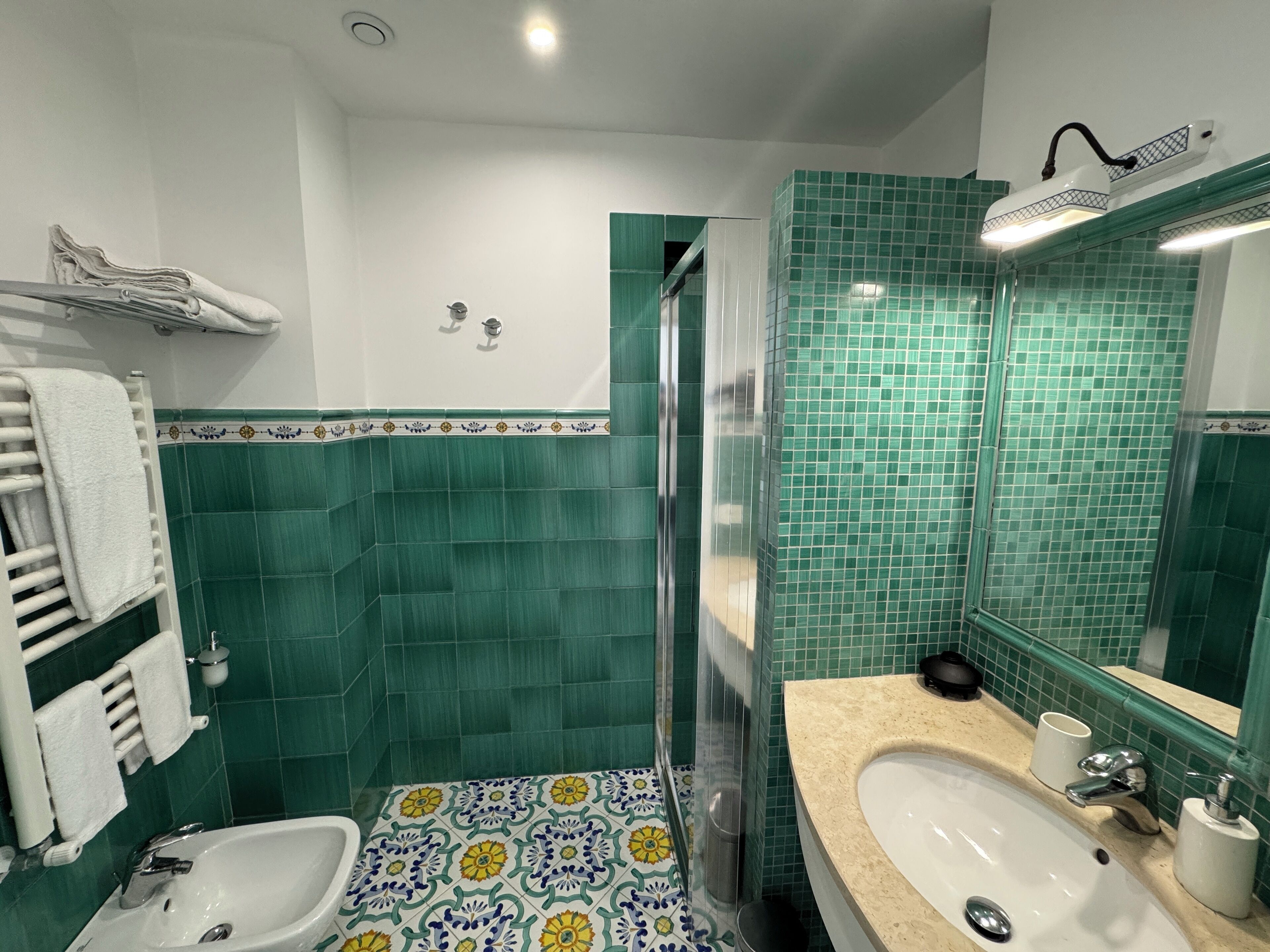 A bathroom with two sinks, a shower, and green tiled walls.