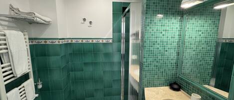 A bathroom with two sinks, a shower, and green tiled walls.
