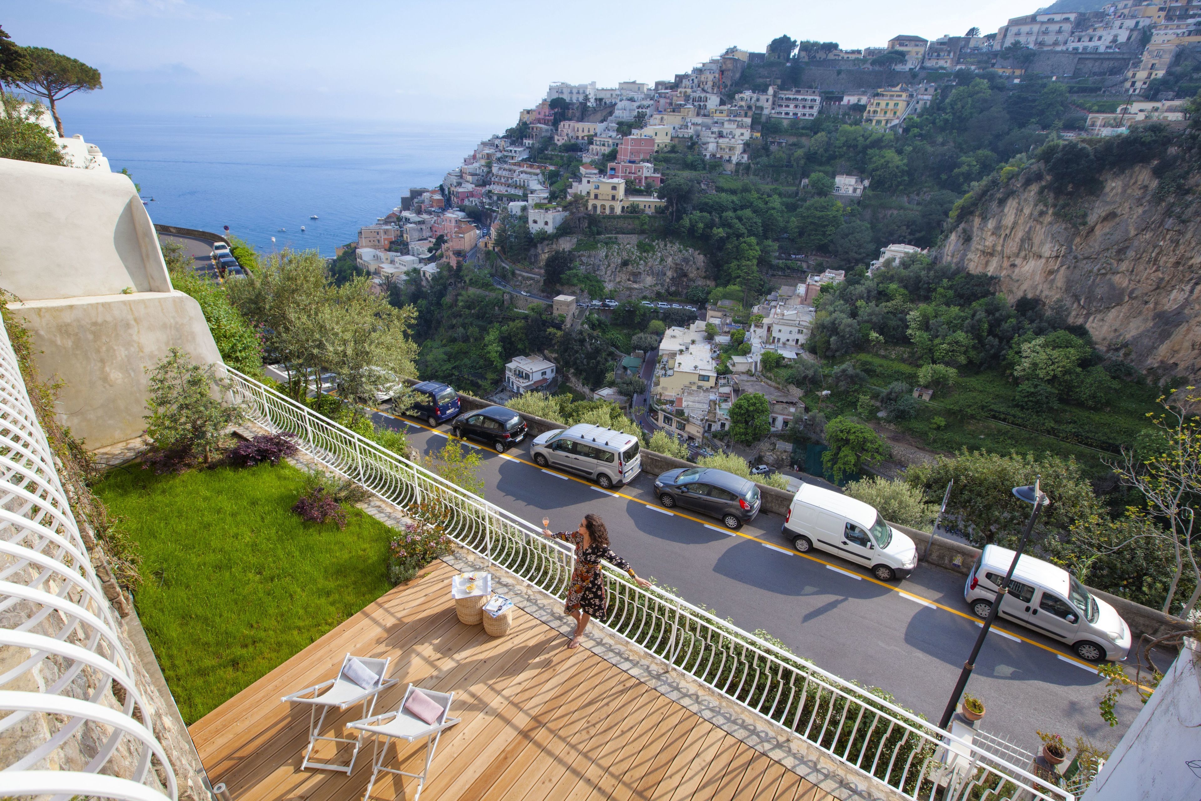 Un balcone con vista su una cittadina costiera, un pontile in legno e una ringhiera.