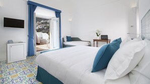 A hotel room with a bed, a desk, a chair, a TV, and a view of a cityscape. - Il Moro di Positano (Positano)