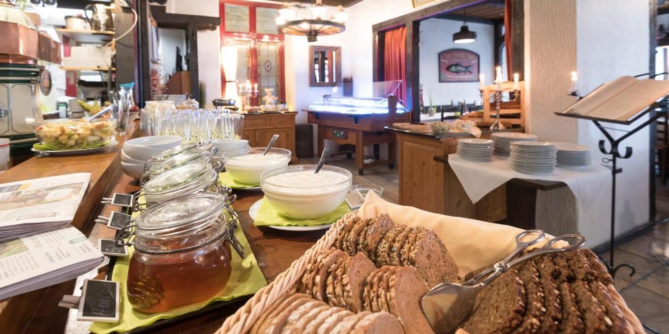 Ein reichhaltiges Buffet mit verschiedenen Speisen, darunter Brot, Suppenschüsseln und Gläser mit Marmelade.