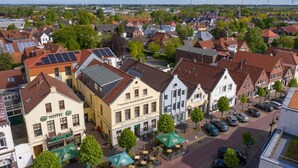 Ein Hotel im traditionellen europäischen Baustil, mit einem zentralen Innenhof, Sitzgelegenheiten im Freien und einem sichtbaren Restaurant.