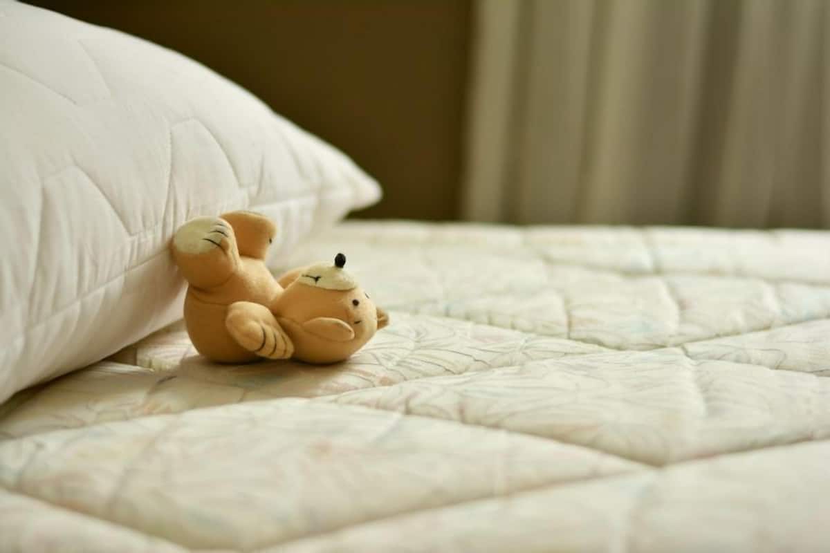 A plush toy on a bed with a quilted cover.