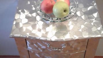 A metallic, hexagonal-patterned cabinet with a glass top holding two apples.