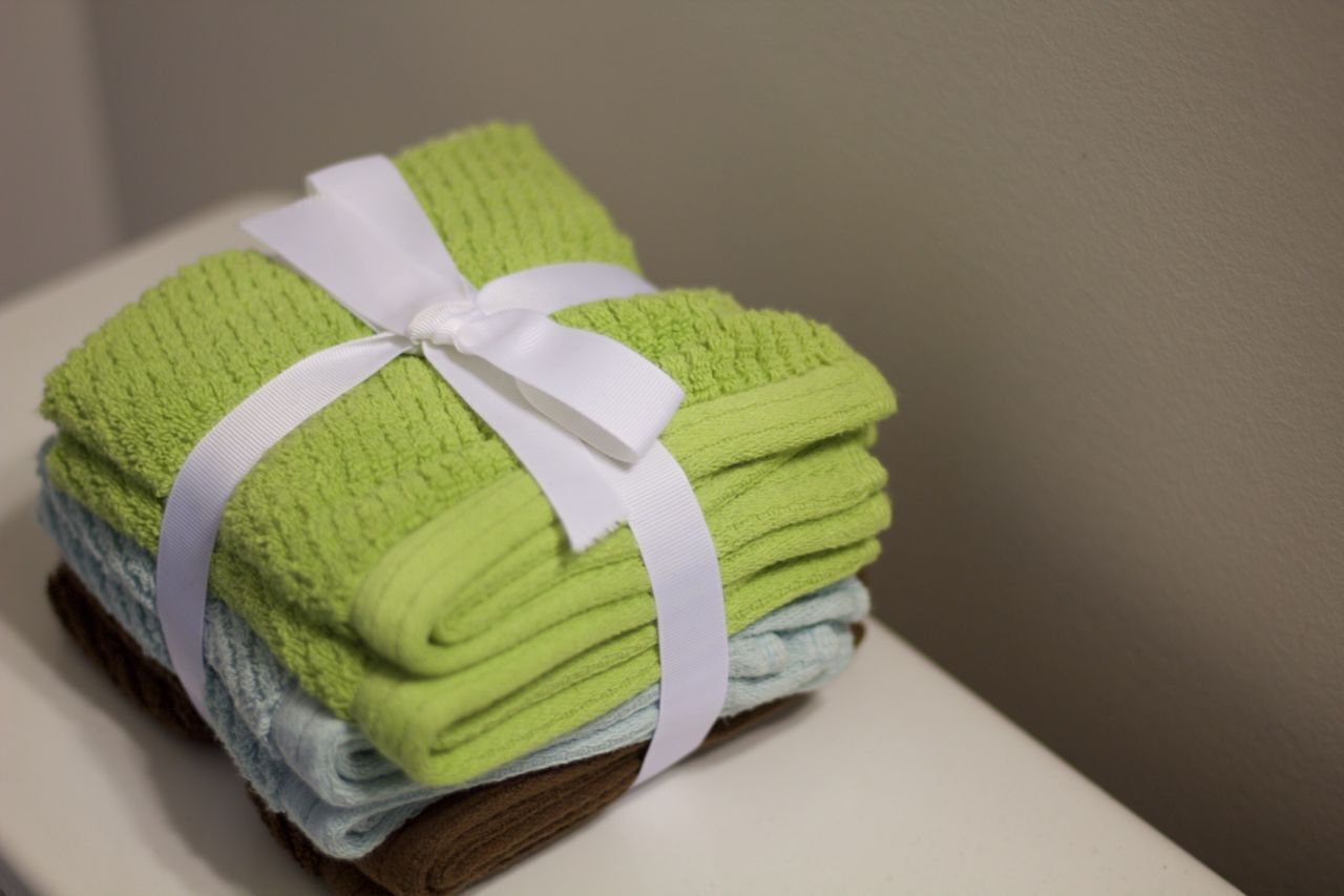 A stack of neatly folded towels tied with a white ribbon, placed on a wooden surface.
