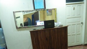 A room with a wooden desk, a mirror, a laptop, and a tiled floor. - Krishna Hostal - Hostel (Quito)