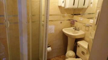 A small bathroom with a glass shower enclosure, a sink, and a toilet.
