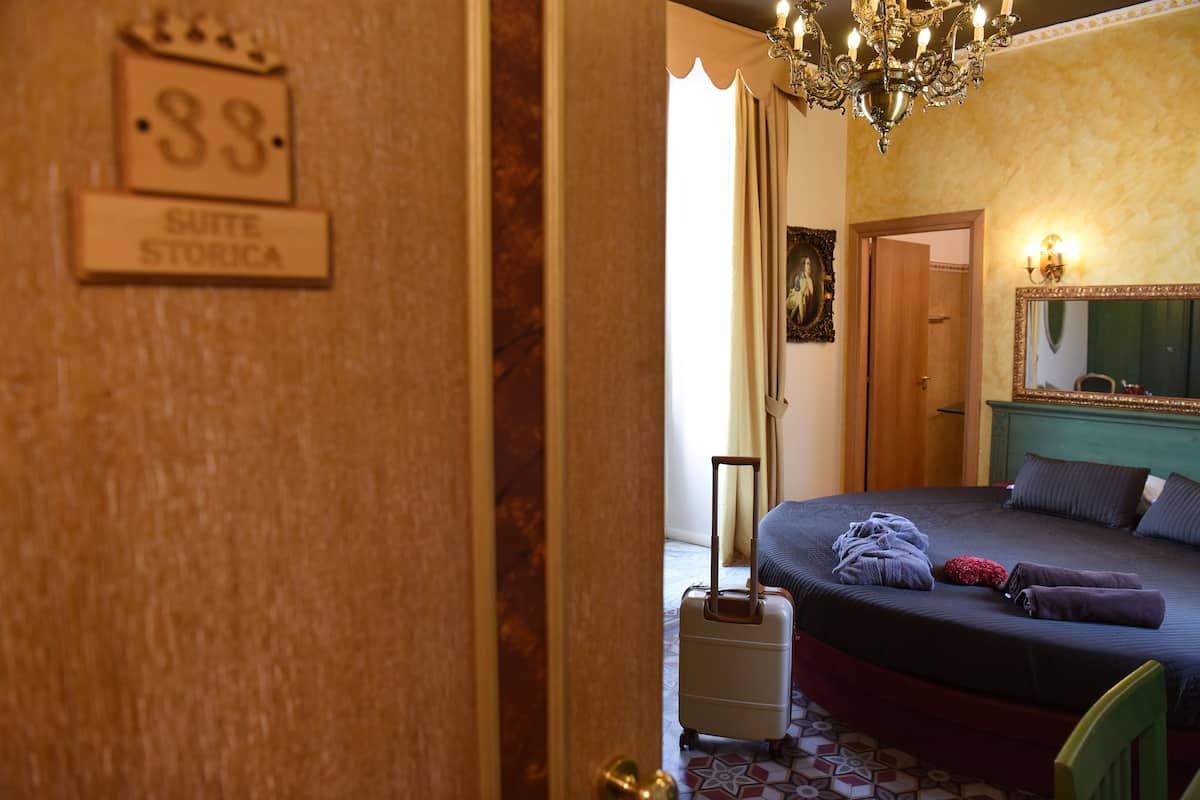 Ein Hotelzimmer mit Bett, Koffer und einer Chandelier.