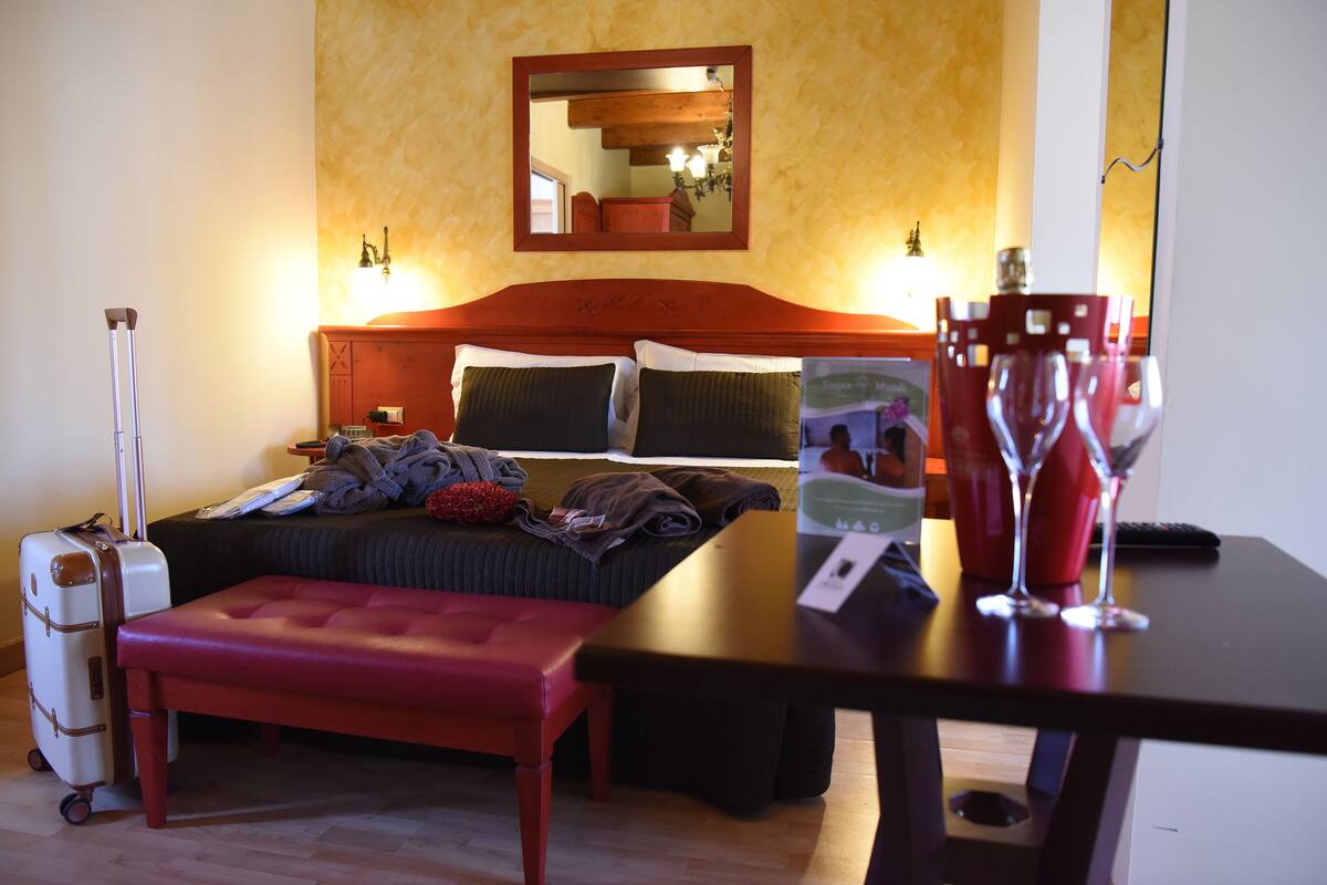 Ein Hotelzimmer mit Bett, Nachttisch, Bank und Koffer.