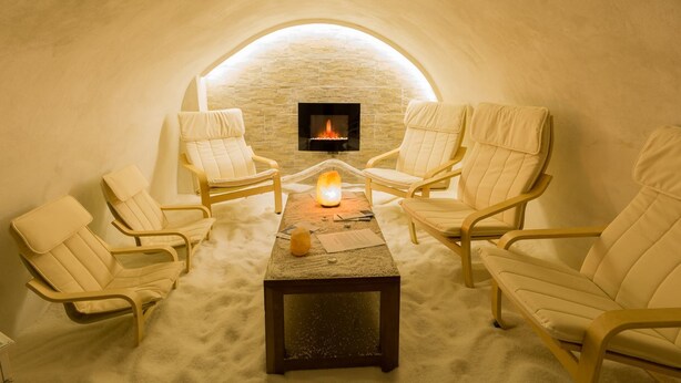 Una habitació amb forma d'igloo, amb una paret de pedra, una llar de foc i quatre cadires al voltant d'una taula.