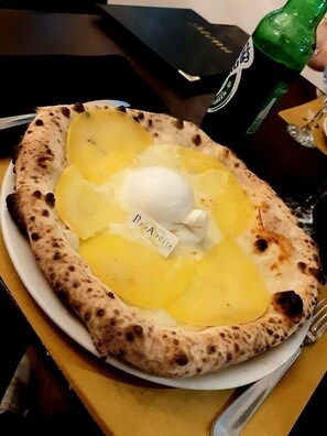 Un plato con pan plano, patatas en rodajas y una cucharada de crema, con la etiqueta 'PIZZA PULIA'.