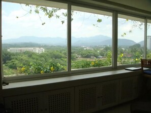 A room with a large window overlooking a green landscape with mountains in the distance. - Condo M Principe (Ixtapa)