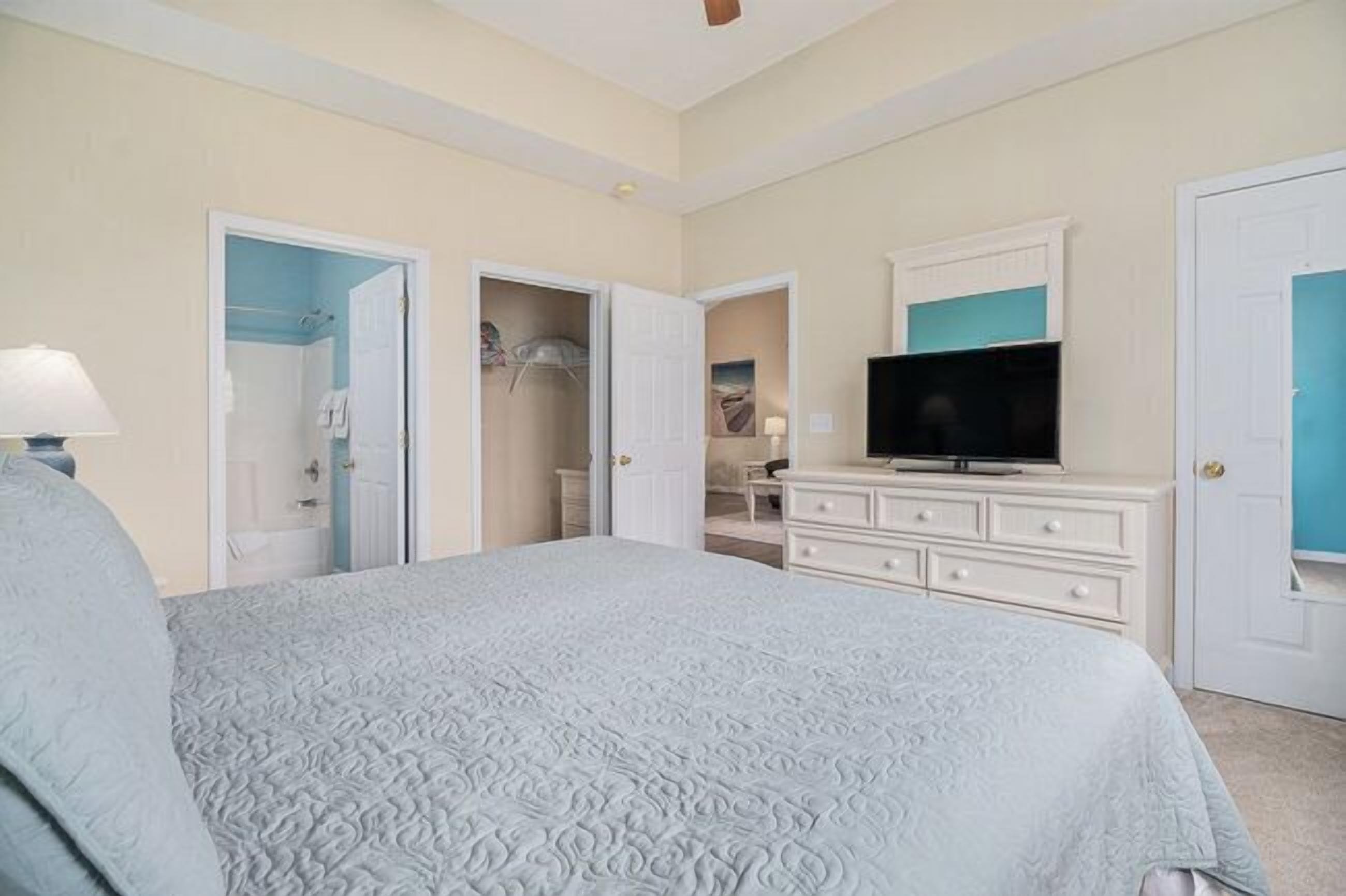 Une chambre à coucher comprenant un lit, une commode, un téléviseur et un placard.