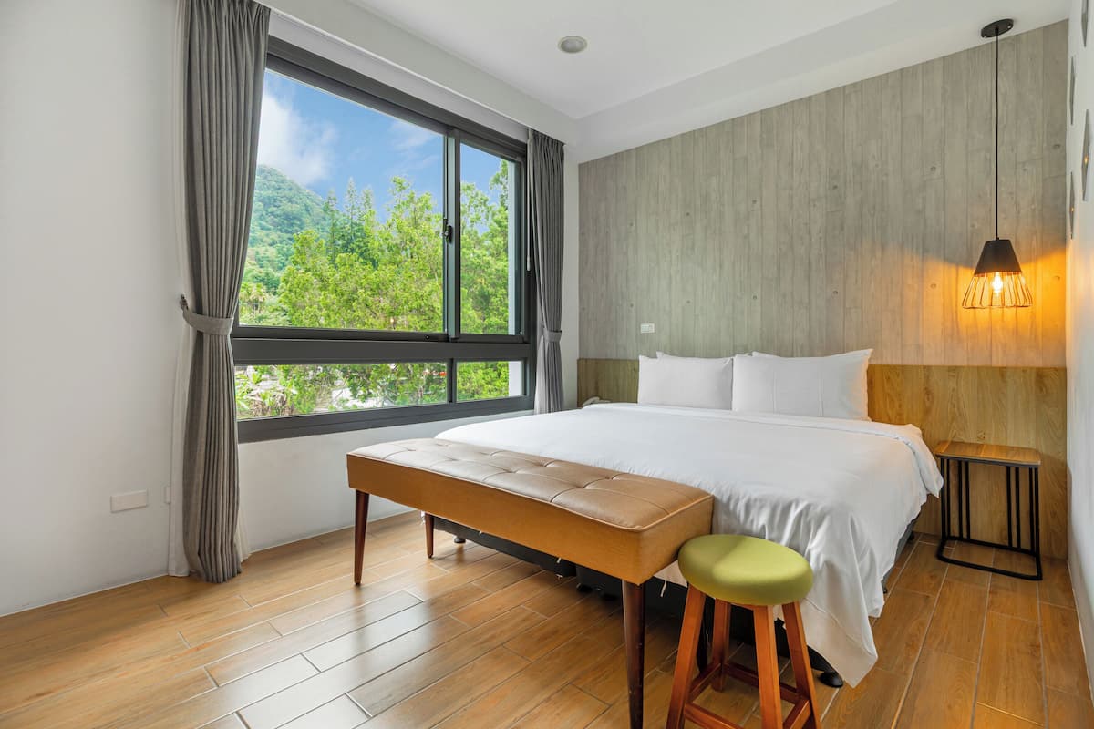 A modern bedroom with a large bed, a bench, and a stool.