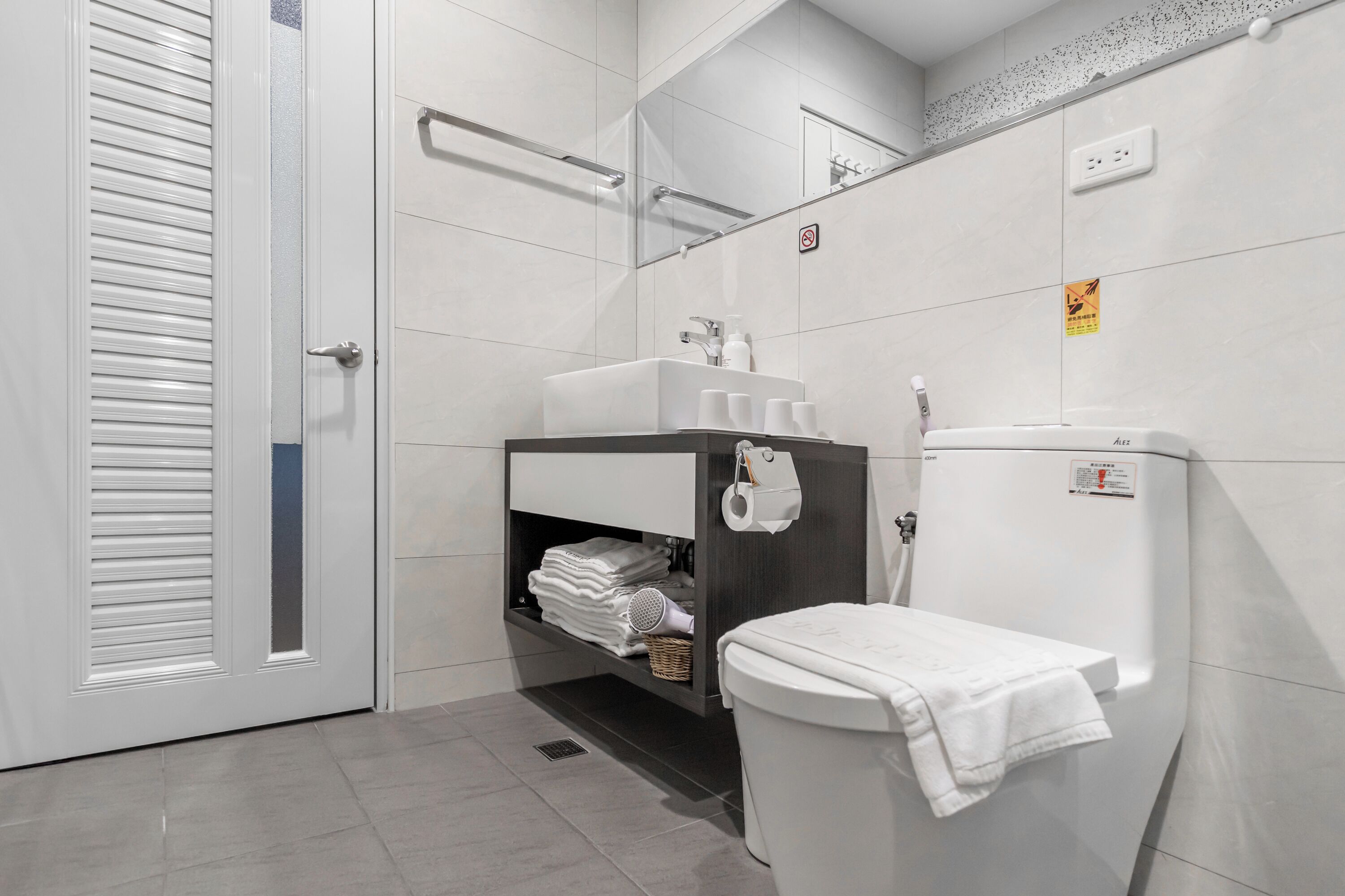 A modern bathroom with a toilet, sink, and mirror.