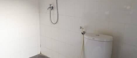 A small, clean bathroom with a toilet, a shower, and a trash bin.