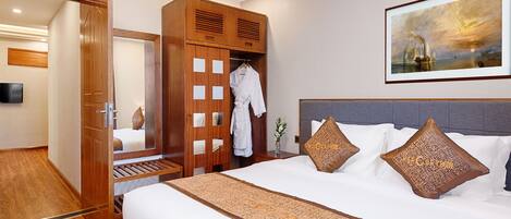 Une chambre d’hôtel avec un grand lit, une armoire en bois, un tableau au mur et un téléviseur fixé au mur.